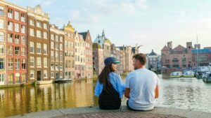 Amsterdam Damrak sunset, happy couple man and woman on a summer evening at the Amsterdam canals